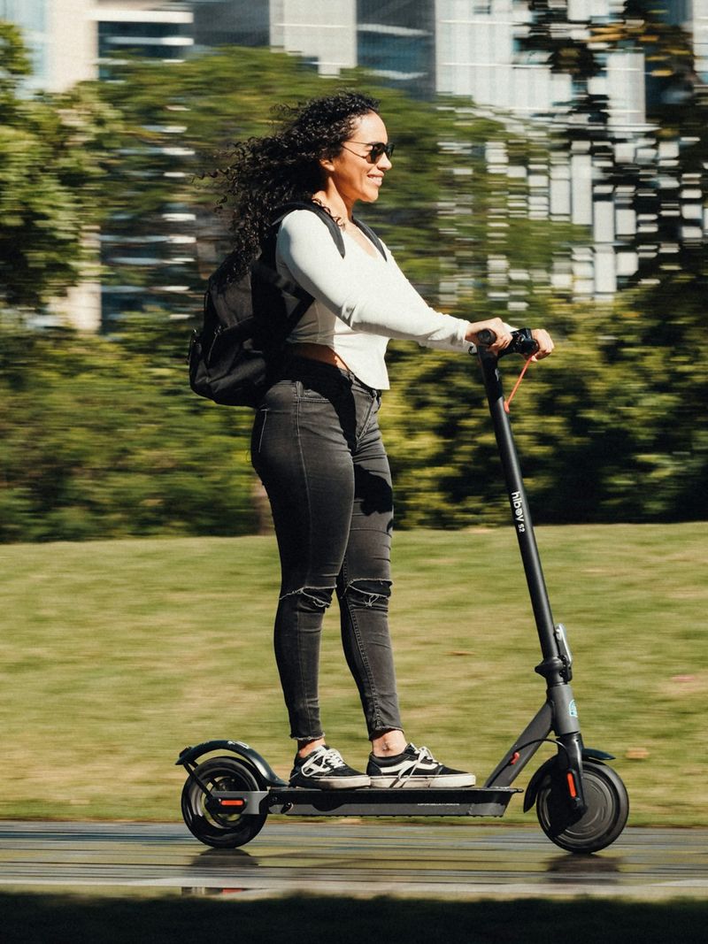 Woman riding an electric scooter (e-scooter) through a park