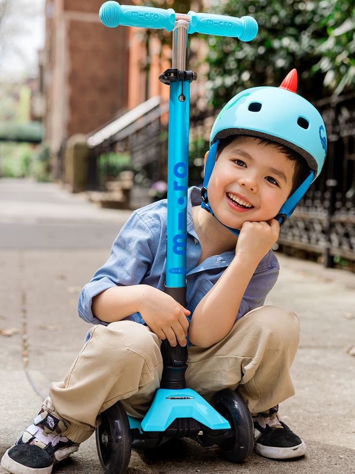 Smiling child in a helmet with a Micro kids' scooter